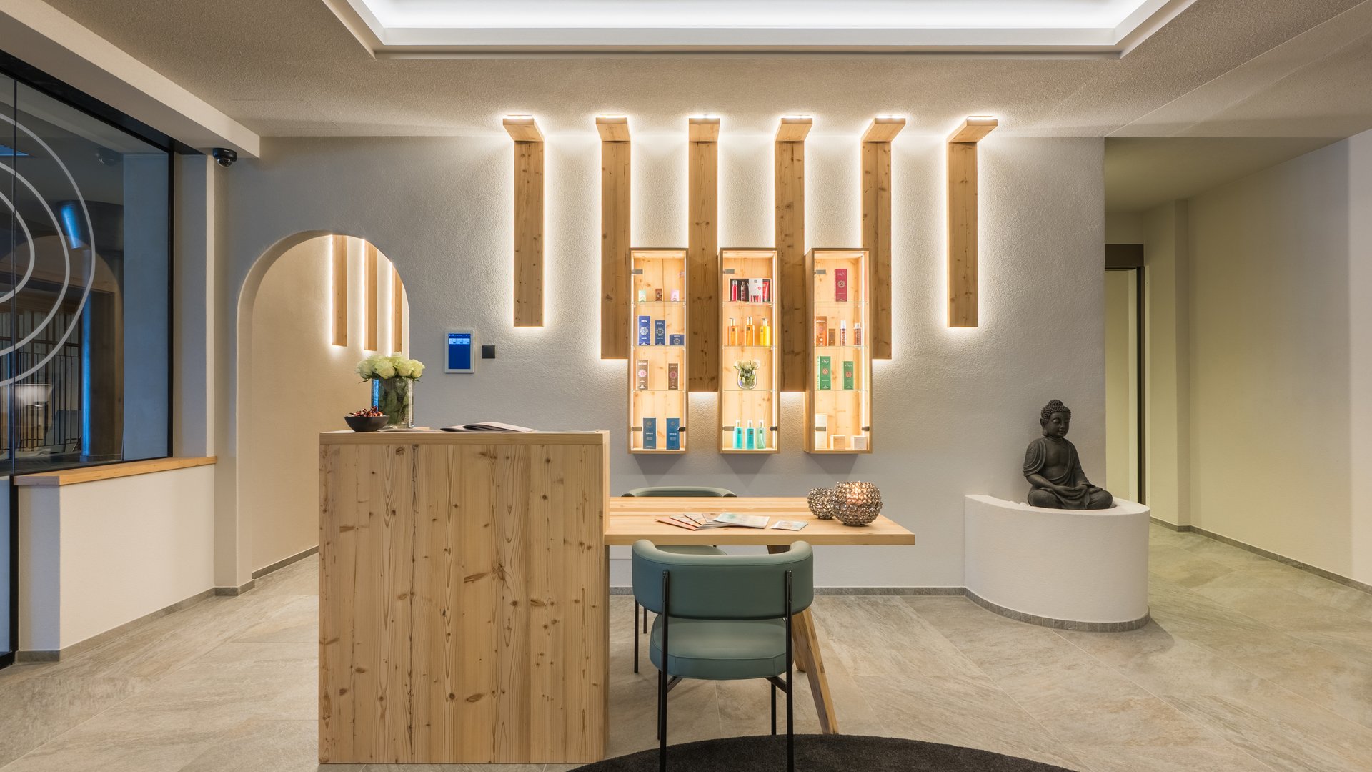 Willkommen in Olang: Hotel Christoph Empfangsbereich mit Holztheke, Stühlen, dekorativer Wandbeleuchtung und Buddha-Statue