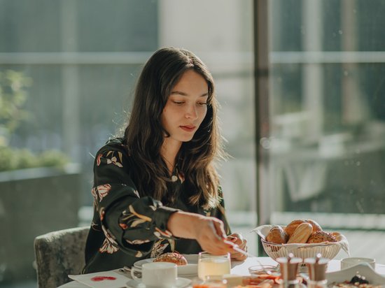 Leichte Wanderung am Kronplatz Frau sitzt am Tisch und genießt ein Frühstück mit Brötchen und Marmelade