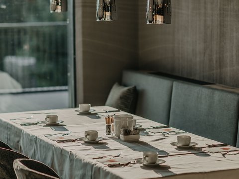 Standardzimmer Hotel Christoph Ein gedeckter Tisch mit Tassen unter modernen Hängelampen in einem Restaurant.