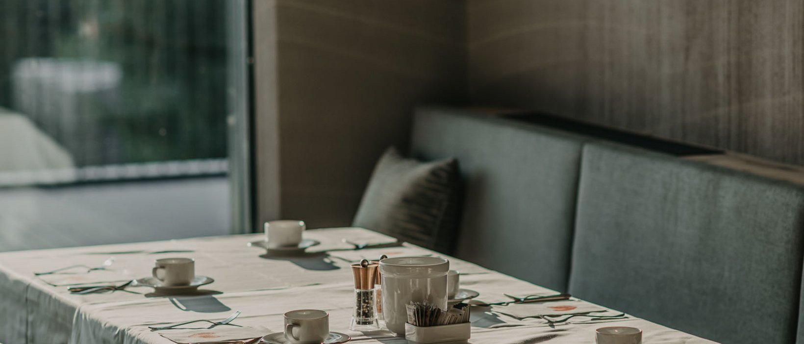 Standardzimmer Hotel Christoph Ein gedeckter Tisch mit Tassen unter modernen Hängelampen in einem Restaurant.