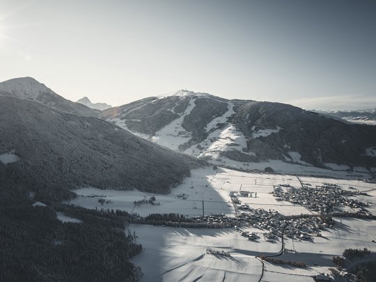 Your Plan de Corones/Kronplatz hotel on the slopes Snow-covered valley with village and mountains in sunlight
