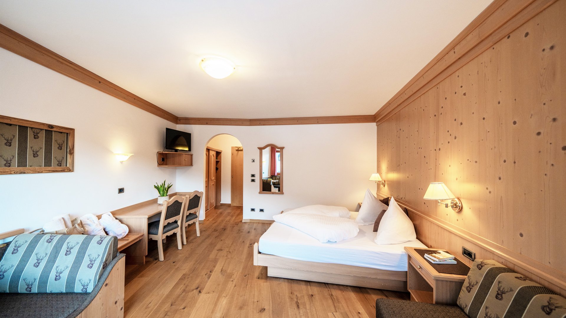 Willkommen in Olang: Hotel Christoph Gemütliches Hotelzimmer mit Holzmöbeln und Doppelbett