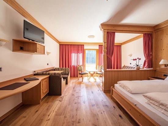 Leichte Wanderung am Kronplatz Helles Hotelzimmer mit Holzmöbeln, Bett, Sitzecke und Fernseher
