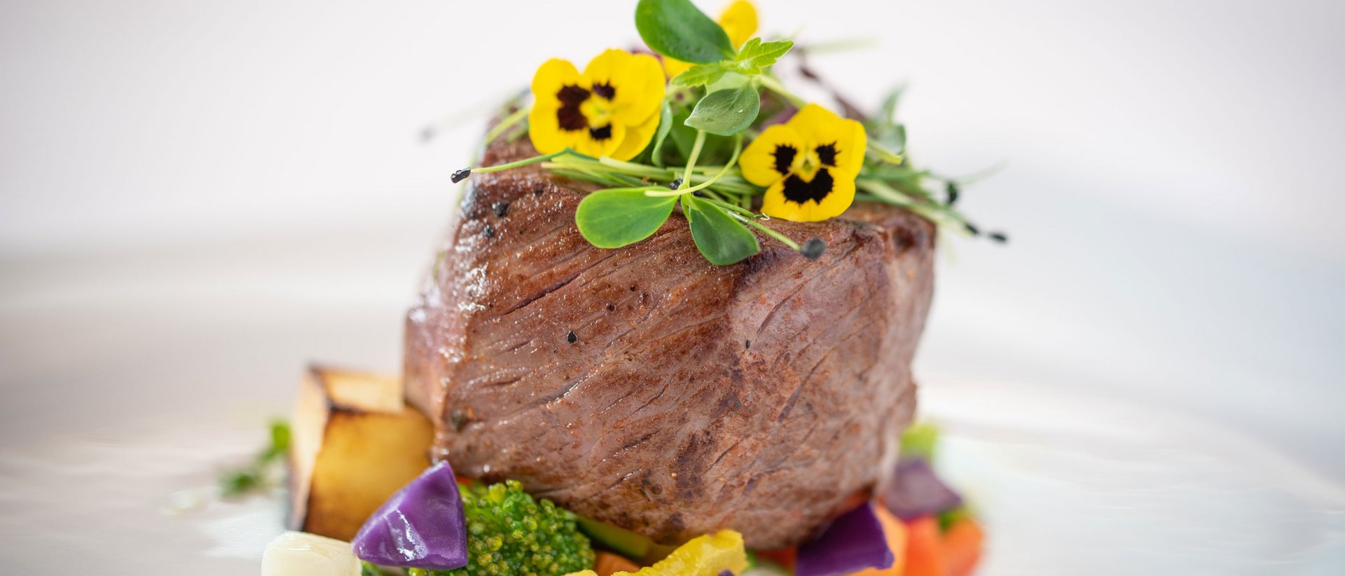 Vorfreude auf Frühlingsgefühle Gourmet-Rinderfilet mit buntem Gemüse und essbaren gelben Blüten