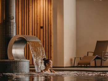 Bewertungen unseres Hotels im Pustertal mit 4 Sternen Frau entspannt im Innenpool mit Wasserfallmassage