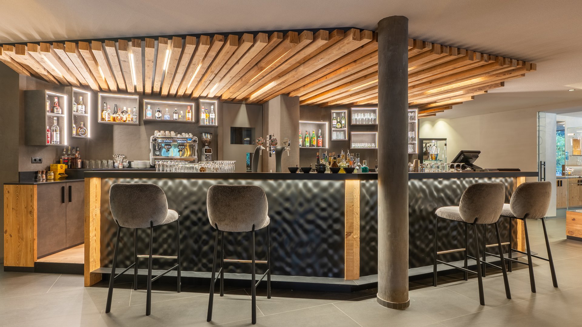 Willkommen in Olang: Hotel Christoph Moderner Hotelbarbereich mit beleuchtetem Holzdekor und Barhockern