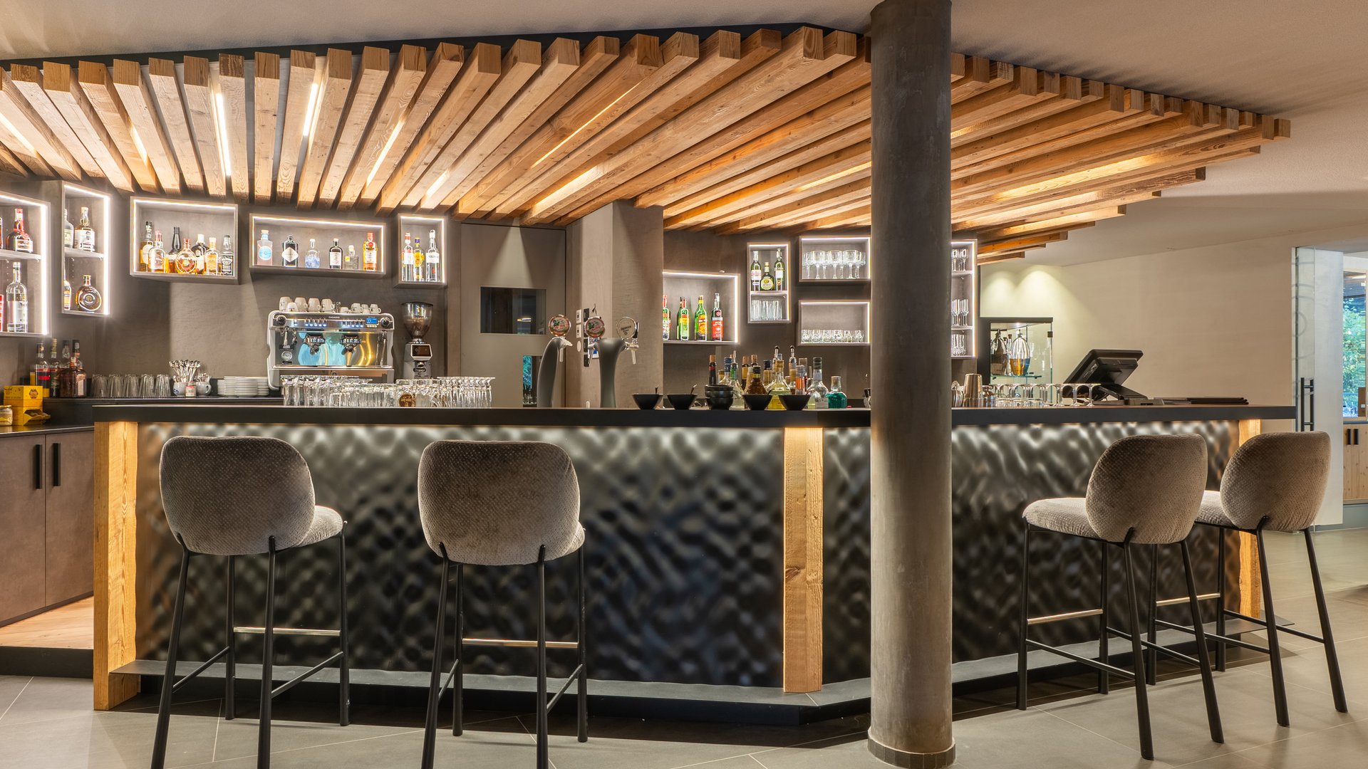 Willkommen in Olang: Hotel Christoph Moderner Hotelbarbereich mit beleuchtetem Holzdekor und Barhockern