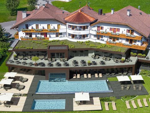Sustainable 4-star hotel in the Dolomites Hotel building with pool and sun terraces in green landscape
