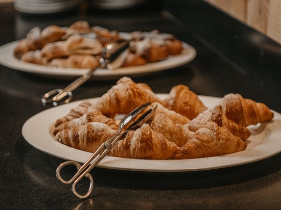 Standardzimmer Hotel Christoph Weiße Teller mit Croissants und Gebäck auf schwarzer Arbeitsfläche