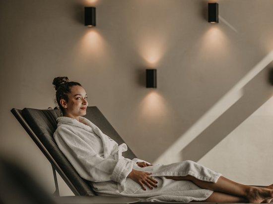 Standardzimmer Hotel Christoph Frau in weißem Bademantel entspannt auf Liegestuhl in Spa-Umgebung