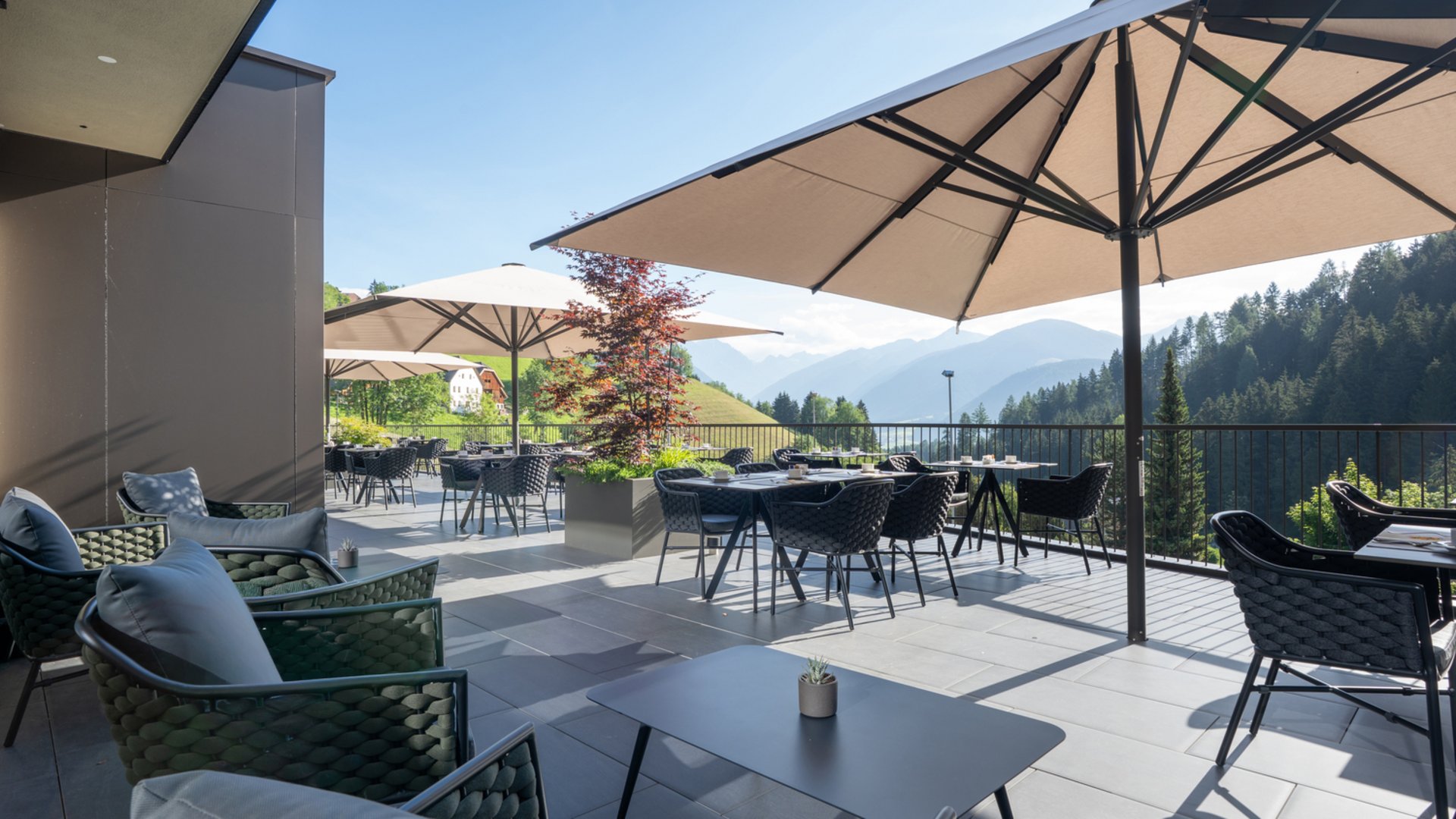 Willkommen in Olang: Hotel Christoph Terrasse mit Tischen, Stühlen und Sonnenschirmen mit Bergblick