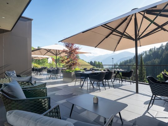Willkommen in Olang: Hotel Christoph Terrasse mit Tischen, Stühlen und Sonnenschirmen mit Bergblick