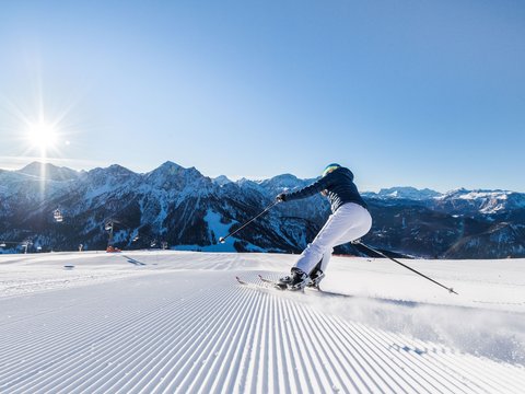 Bewertungen unseres Hotels im Pustertal mit 4 Sternen Skifahrer fährt auf frisch präparierter Piste vor sonnigen Bergen