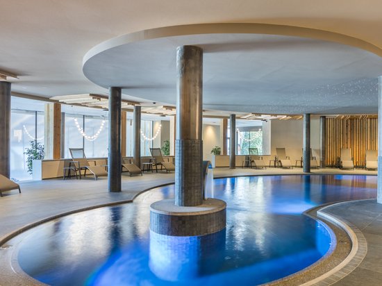 The right room for your Lago di Braies/Pragser Wildsee holiday Modern indoor pool with blue illuminated water and lounge chairs