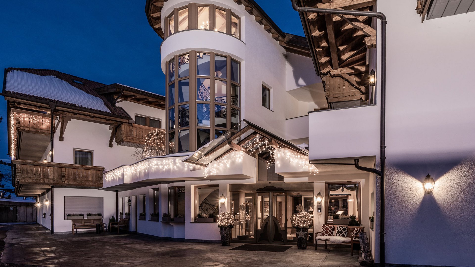 Sustainable 4-star hotel in the Dolomites Lit entrance of a modern alpine house at dusk