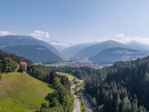 Fitness am Pragser Wildsee: Übernachtung im Hotel Christoph Bergtal mit Wald, Wiesen und Dorf unter blauem Himmel