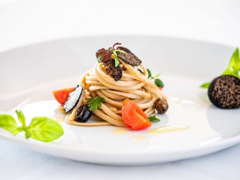 Fitness am Pragser Wildsee: Übernachtung im Hotel Christoph Elegante Pasta mit schwarzen Trüffelscheiben, Tomaten und Kräutern auf weißem Teller