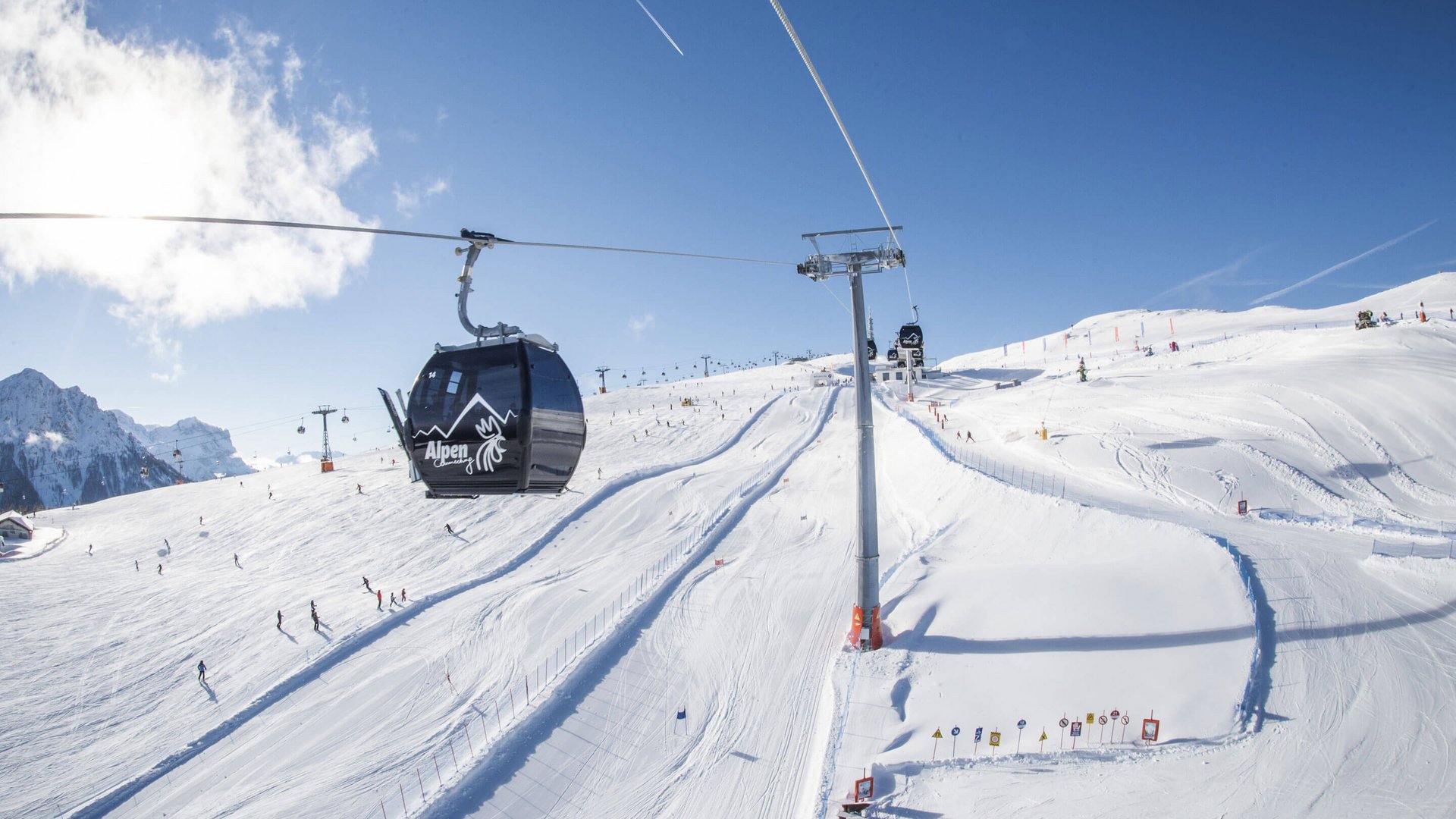 Willkommen in Olang: Hotel Christoph Skilift und Gondel am sonnigen schneebedeckten Berg mit Skifahrern
