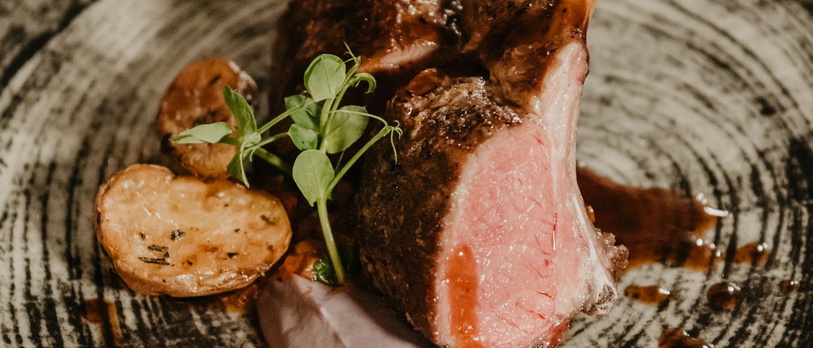 Sustainable 4-star hotel in the Dolomites Grilled lamb chops with potatoes and sauce on a decorative plate