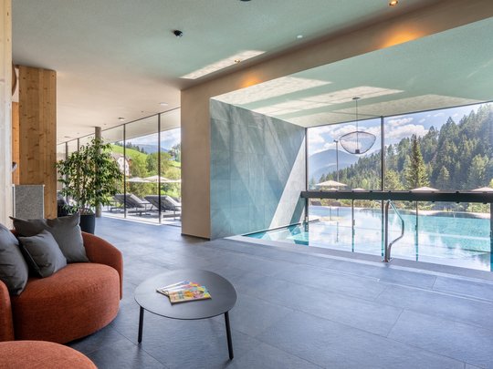 Willkommen in Olang: Hotel Christoph Moderner Wellnessbereich mit Indoor-Pool und Aussicht auf Berge und Wälder