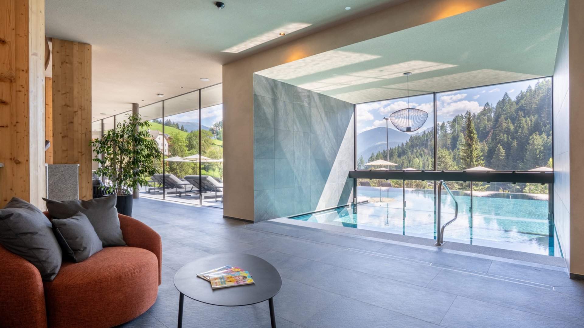 Willkommen in Olang: Hotel Christoph Moderner Wellnessbereich mit Indoor-Pool und Aussicht auf Berge und Wälder
