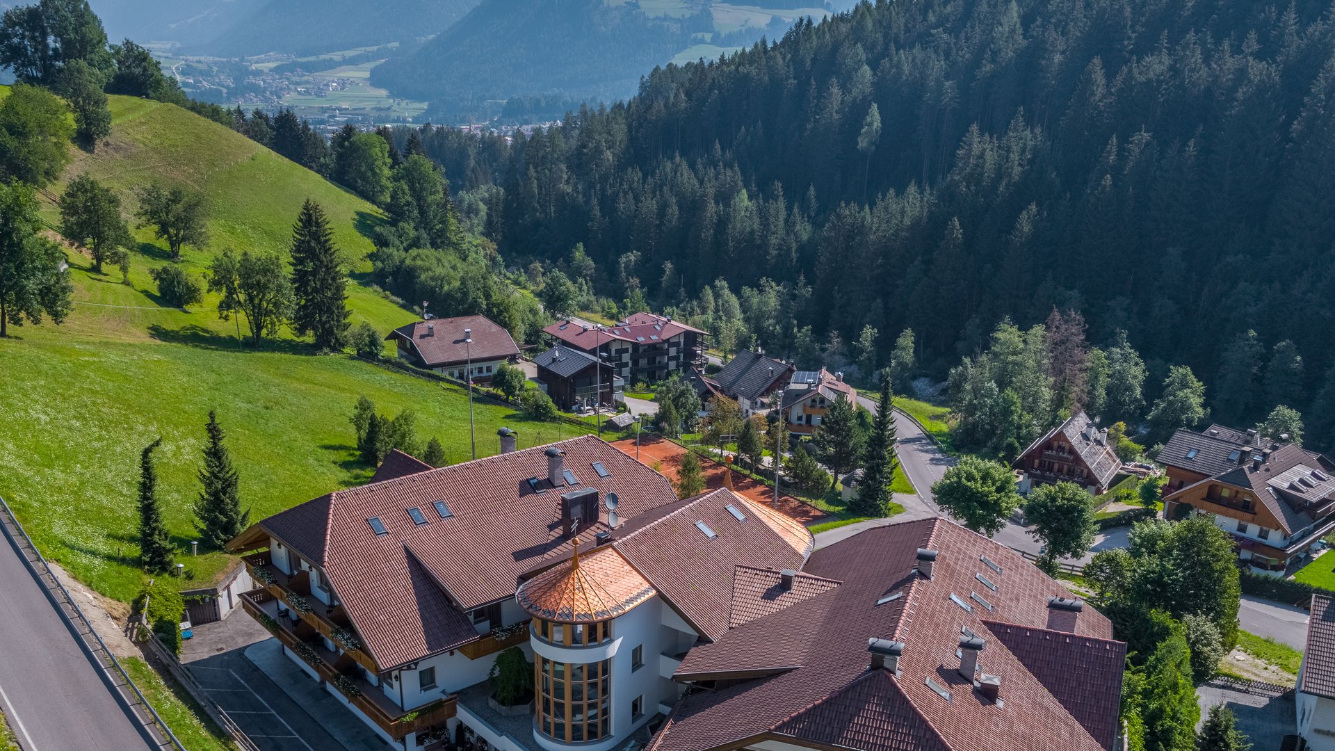 Willkommen in Olang: Hotel Christoph Hotel Christoph mit Bergkulisse und Wald in sonniger Landschaft