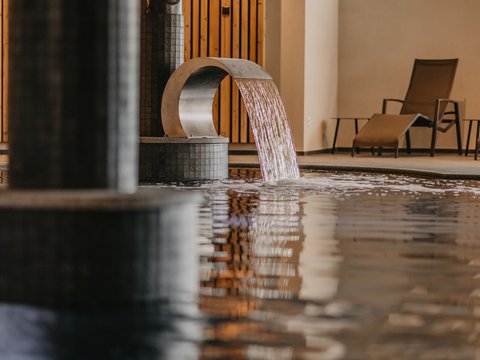 Fitness am Pragser Wildsee: Übernachtung im Hotel Christoph Moderner Wellness-Pool mit Wasserdusche und Liegestühlen im Hintergrund