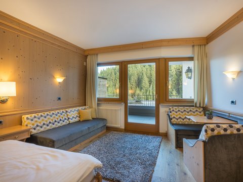Sustainable 4-star hotel in the Dolomites Cozy hotel room with balcony and forest view